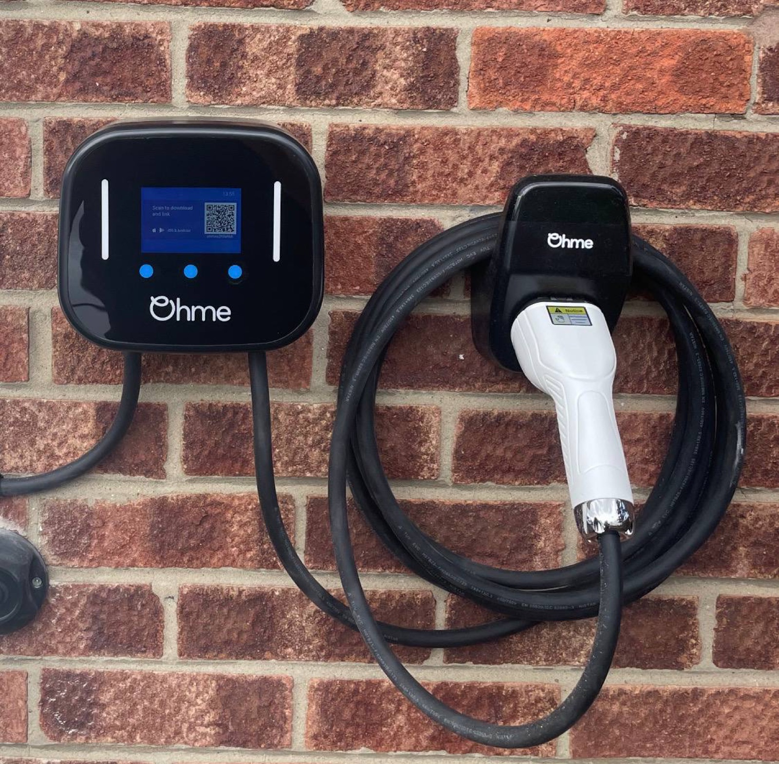 Ohme EV charger with display screen installed on brick wall