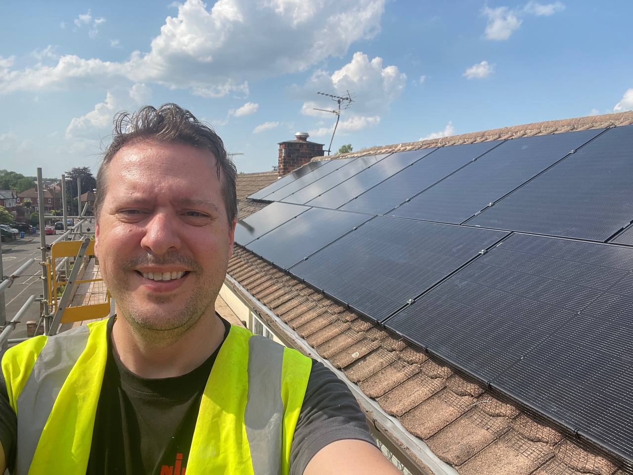 Nick beside a completed roof-mounted solar panel installation