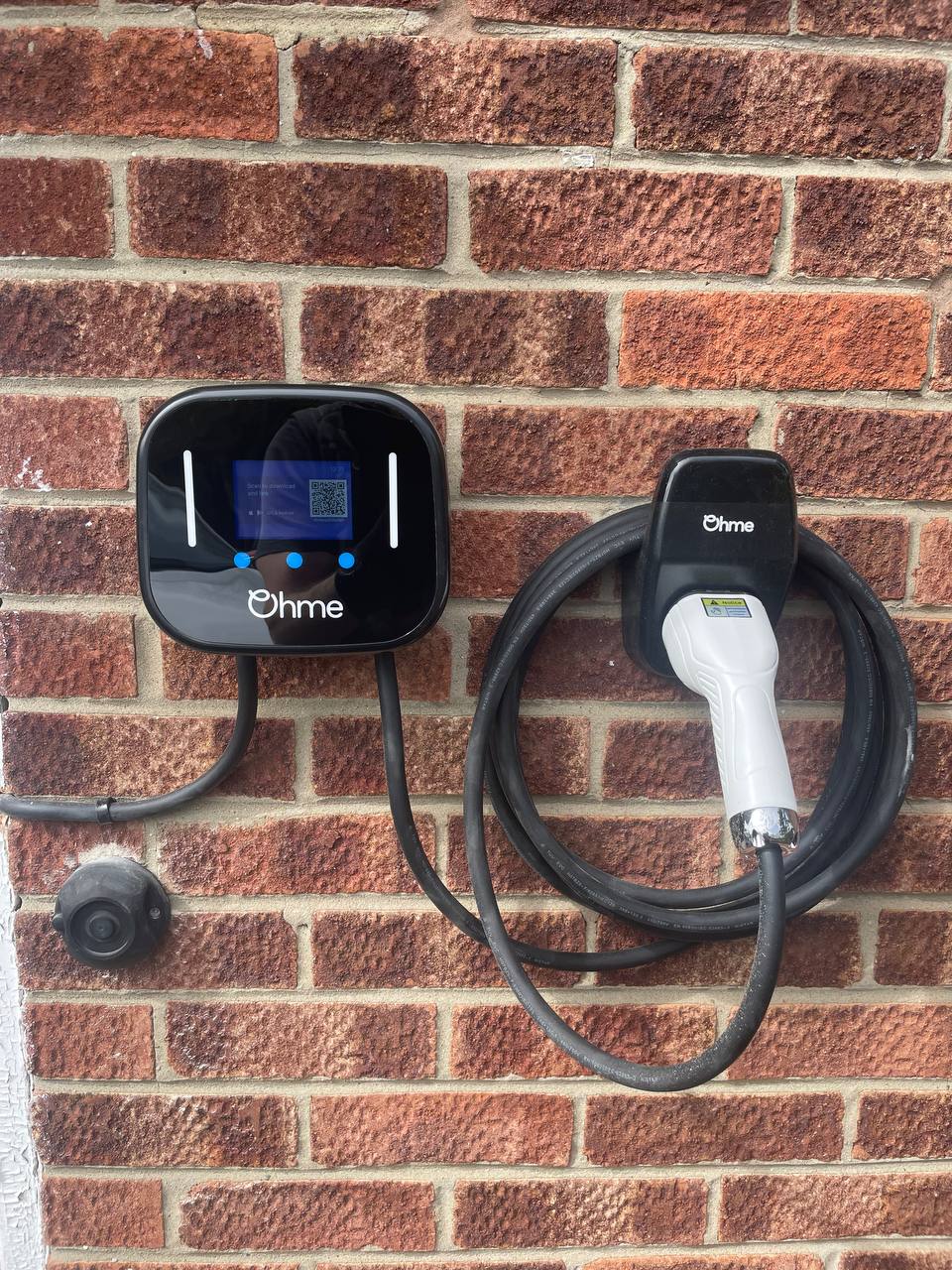 Ohme EV charger installed on a brick wall