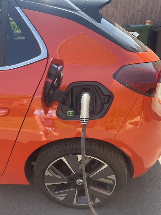 Electric car plugged in and charging on a driveway