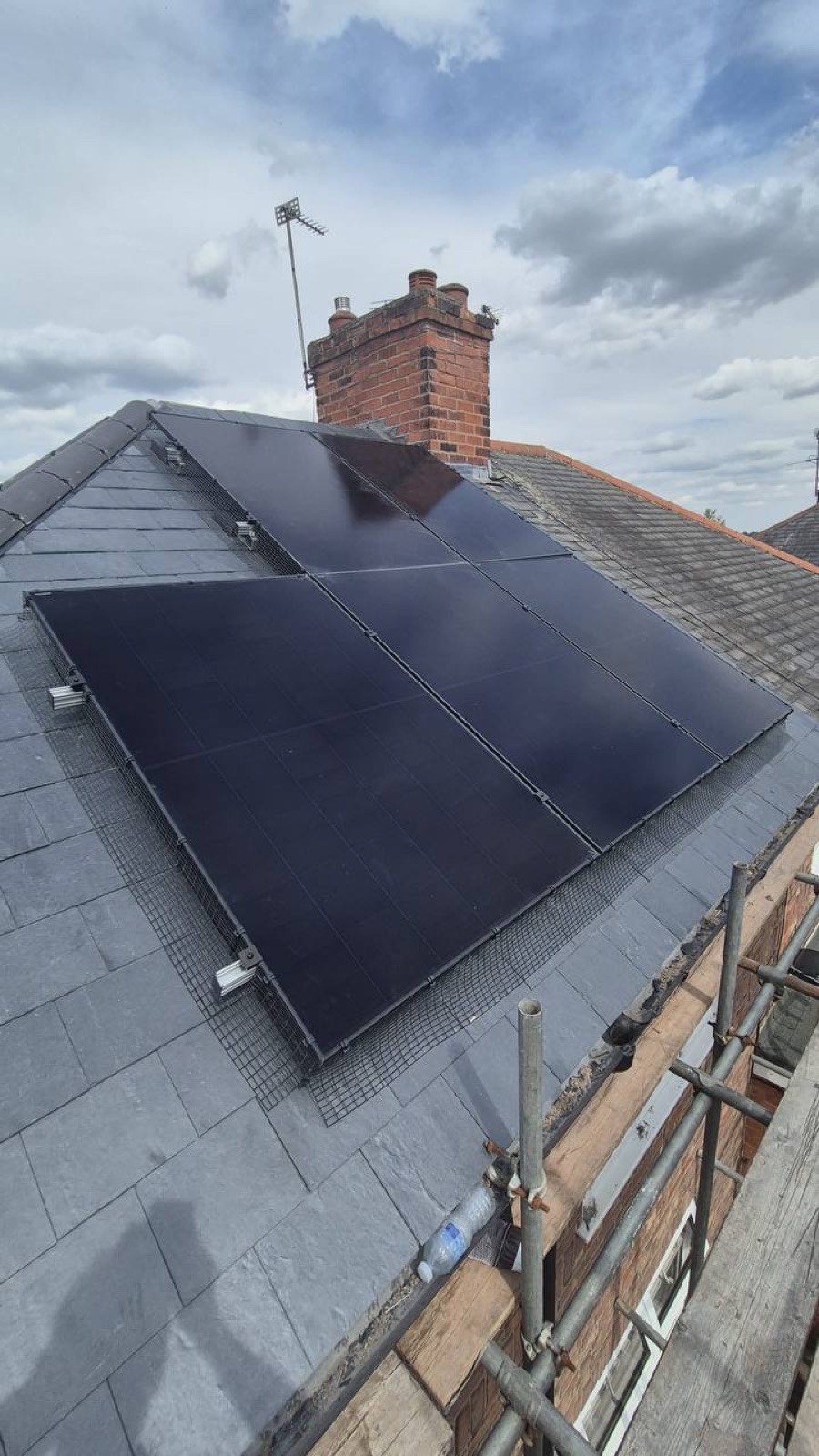 Black solar panels on a slate roof with bird guard mesh fitted