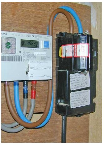Real photograph of an older black plastic UK electricity service cut-out beside a meter