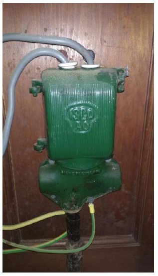 Real photograph of an older green metal-clad UK electricity service cut-out