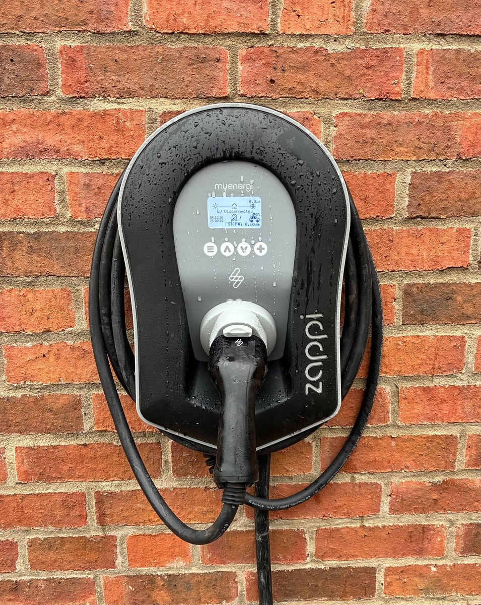myenergi Zappi EV charger with tethered Type 2 cable installed on a red brick wall by E-Fix